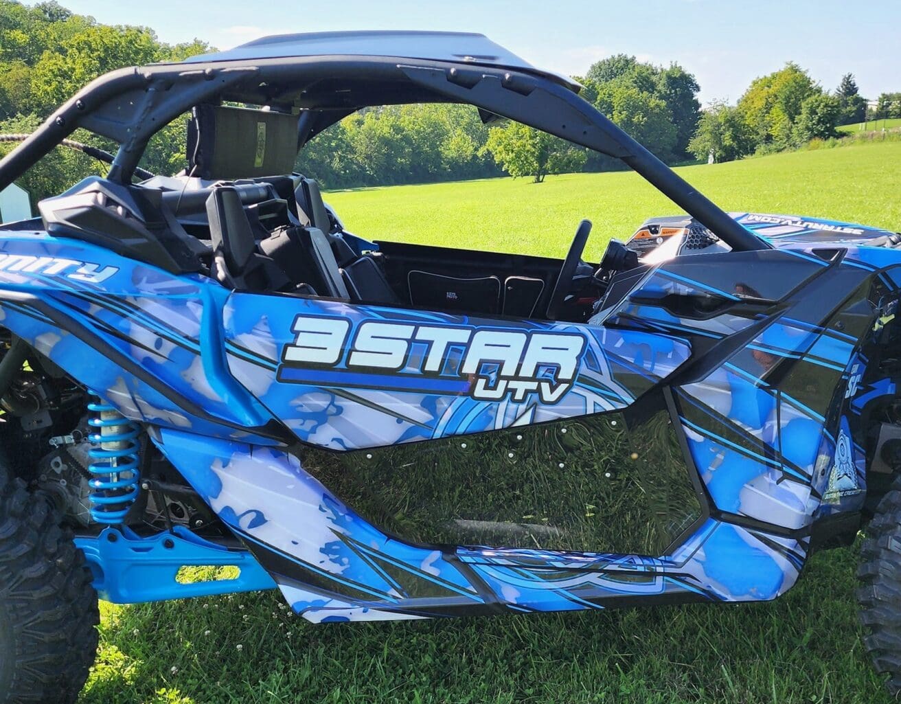 A blue and black three star atv parked in the grass.