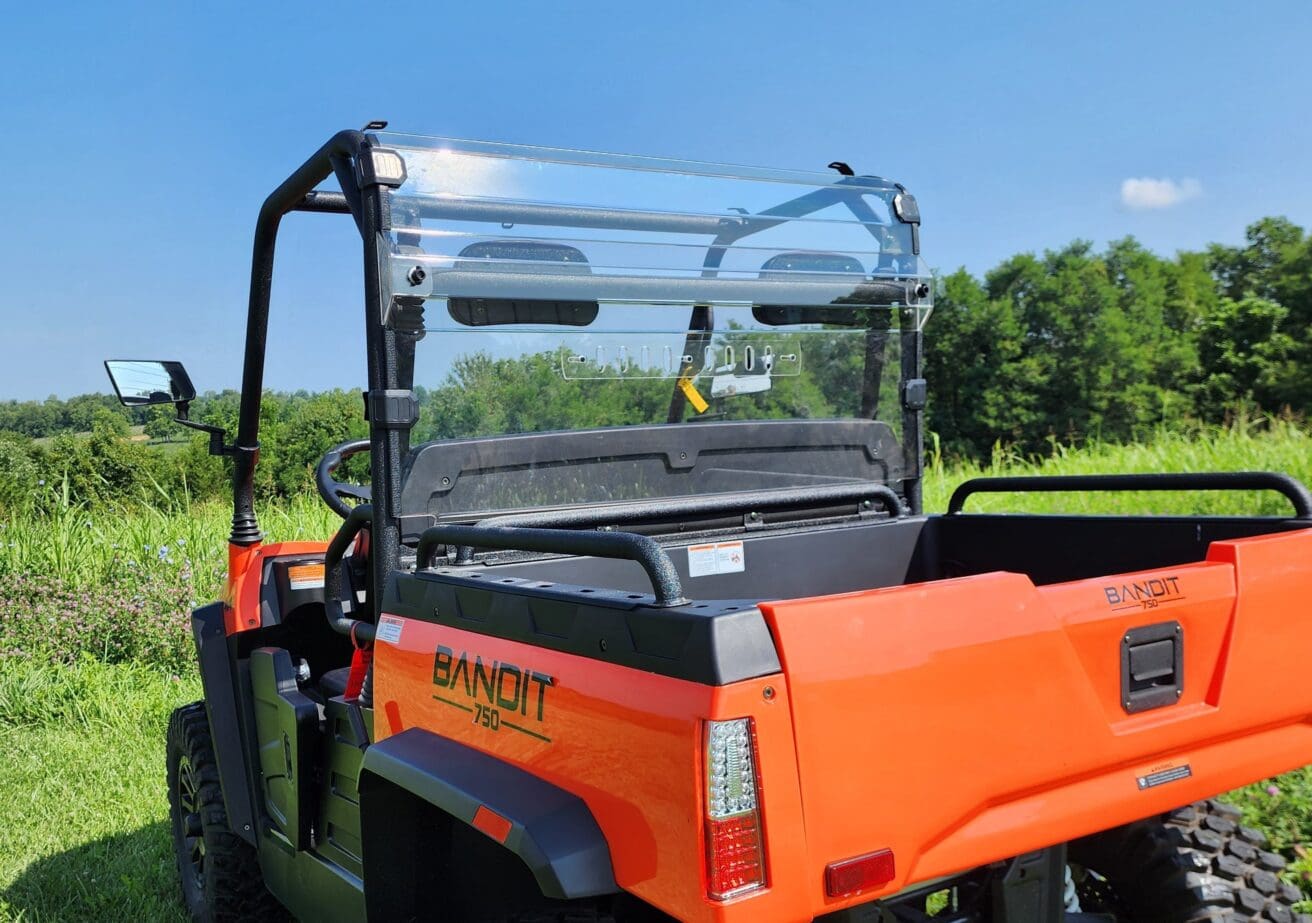 A bright orange utility vehicle parked in the grass.