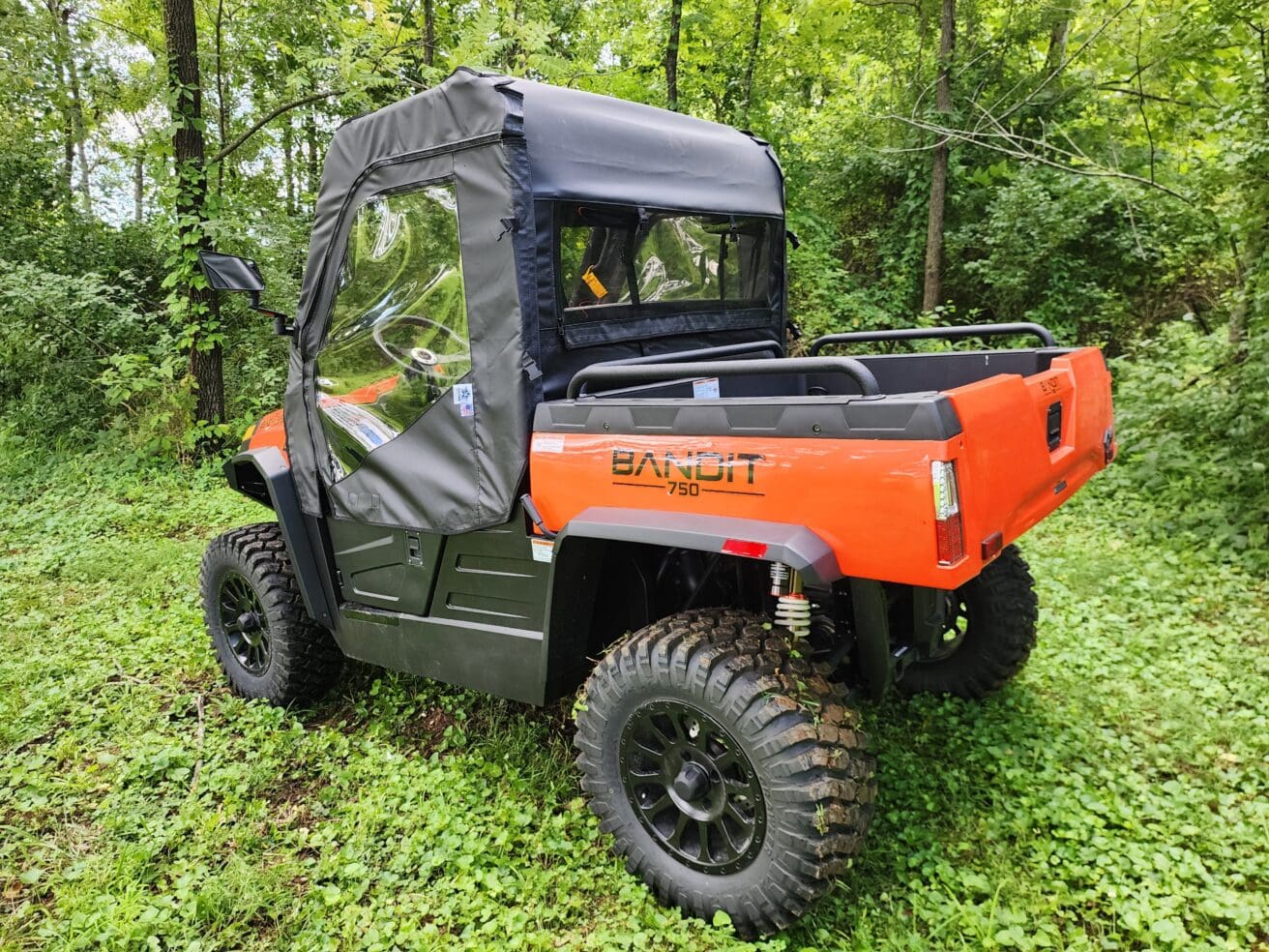 A man riding in the back of an orange utility vehicle.