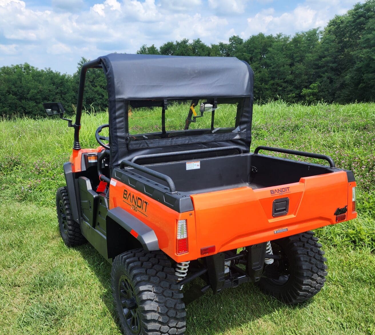 A bright orange utility vehicle parked in the grass.