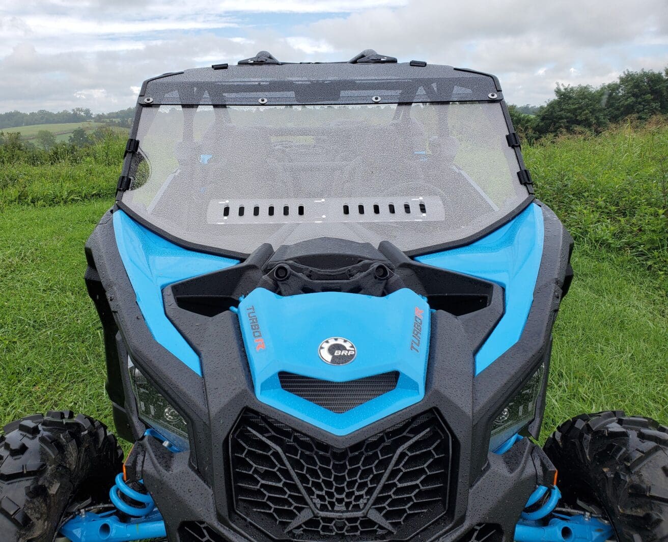 A close up of the front windshield on a blue and black atv.