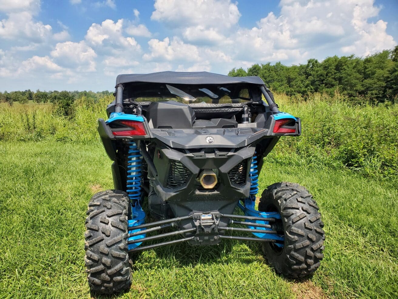 A blue and black atv parked in the grass.