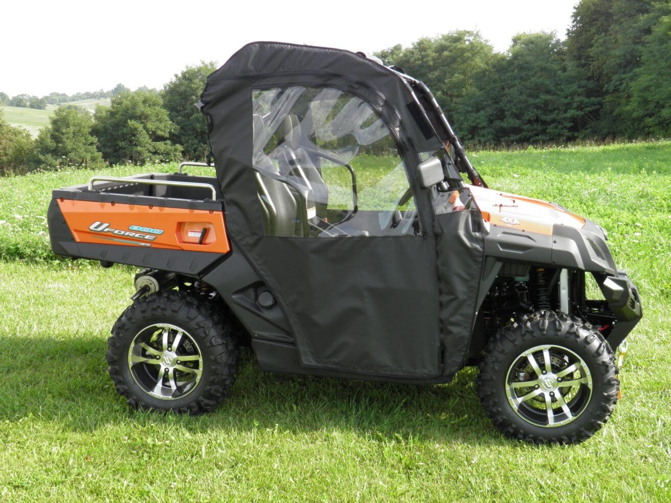 A black and orange utility vehicle parked in the grass.