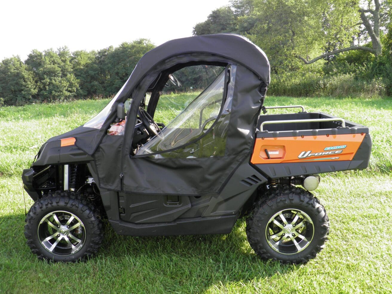 A black and orange utility vehicle parked in the grass.