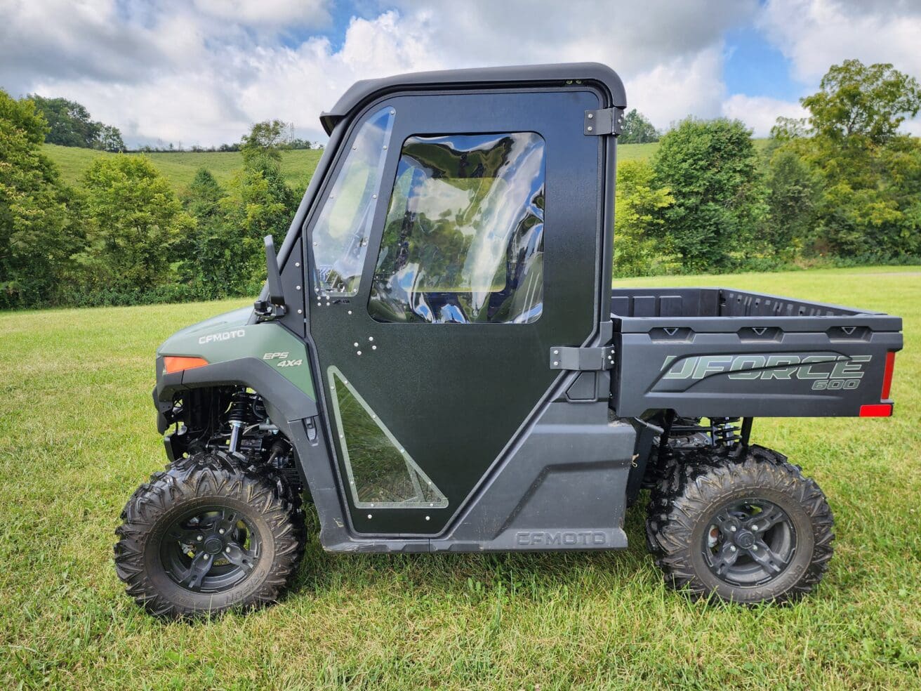 A green utility vehicle parked in the grass.