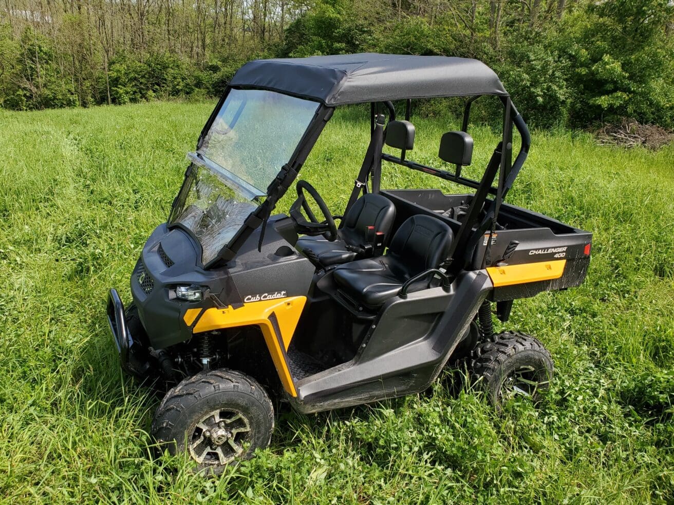 A yellow and black utility vehicle parked in the grass.