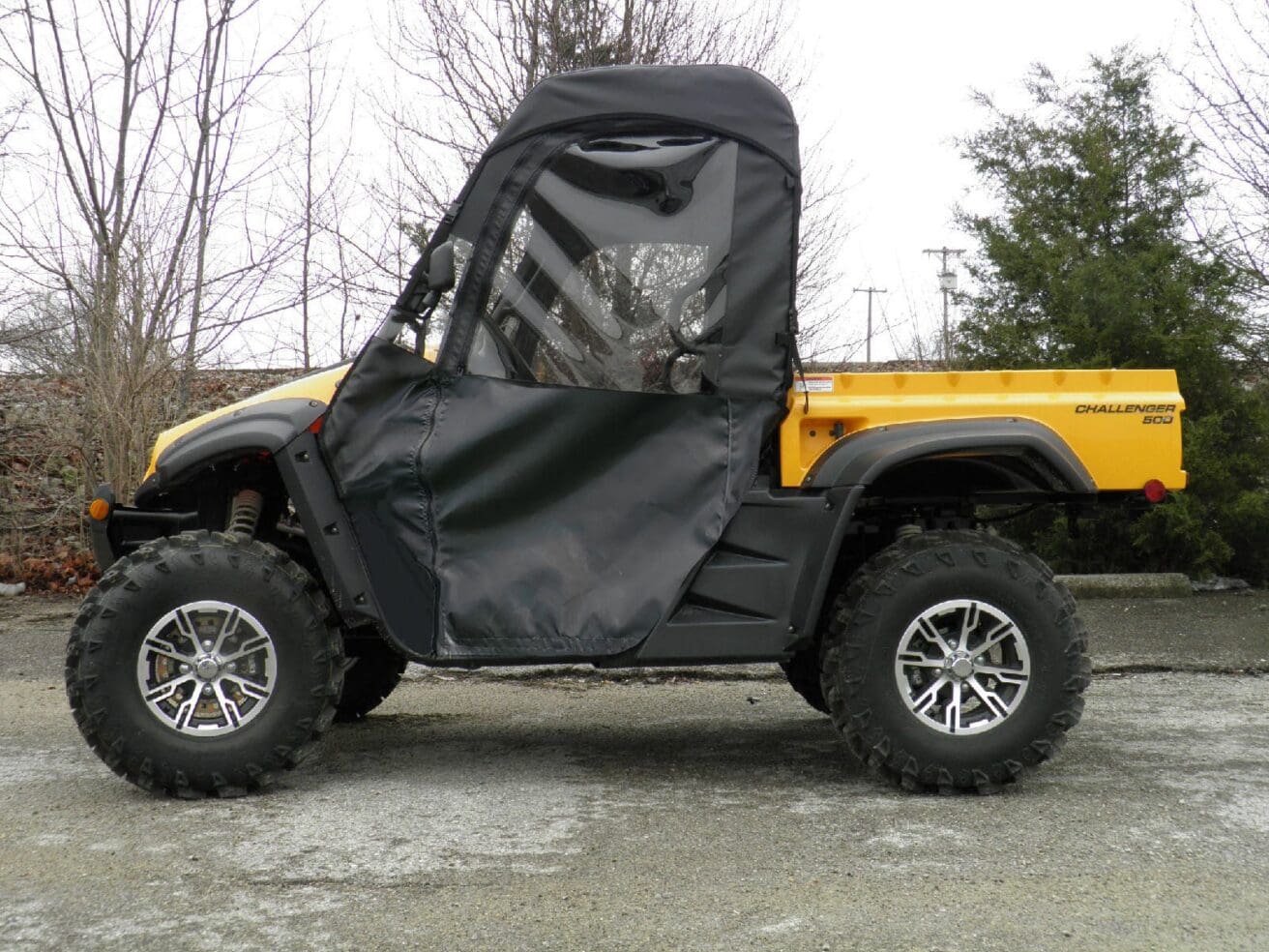 A yellow and black four wheeler with a tarp on the back.