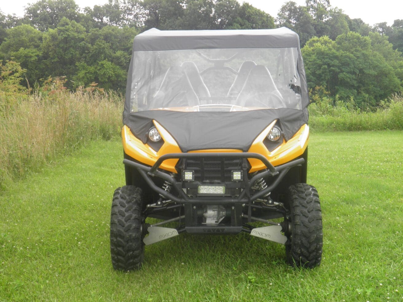 A yellow and black four wheeler parked in the grass.