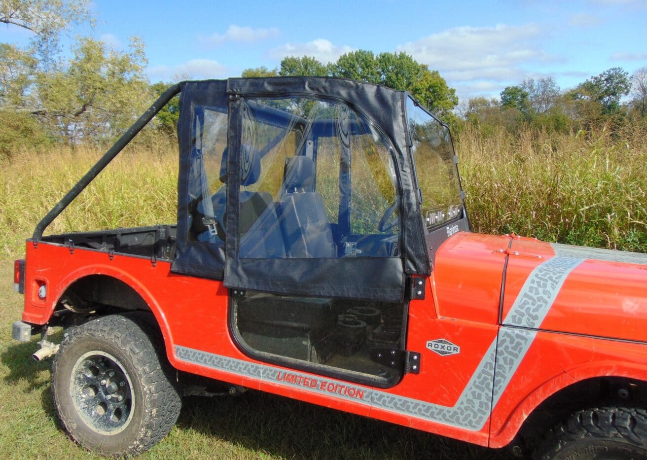 A red jeep with a black top and blue trim.