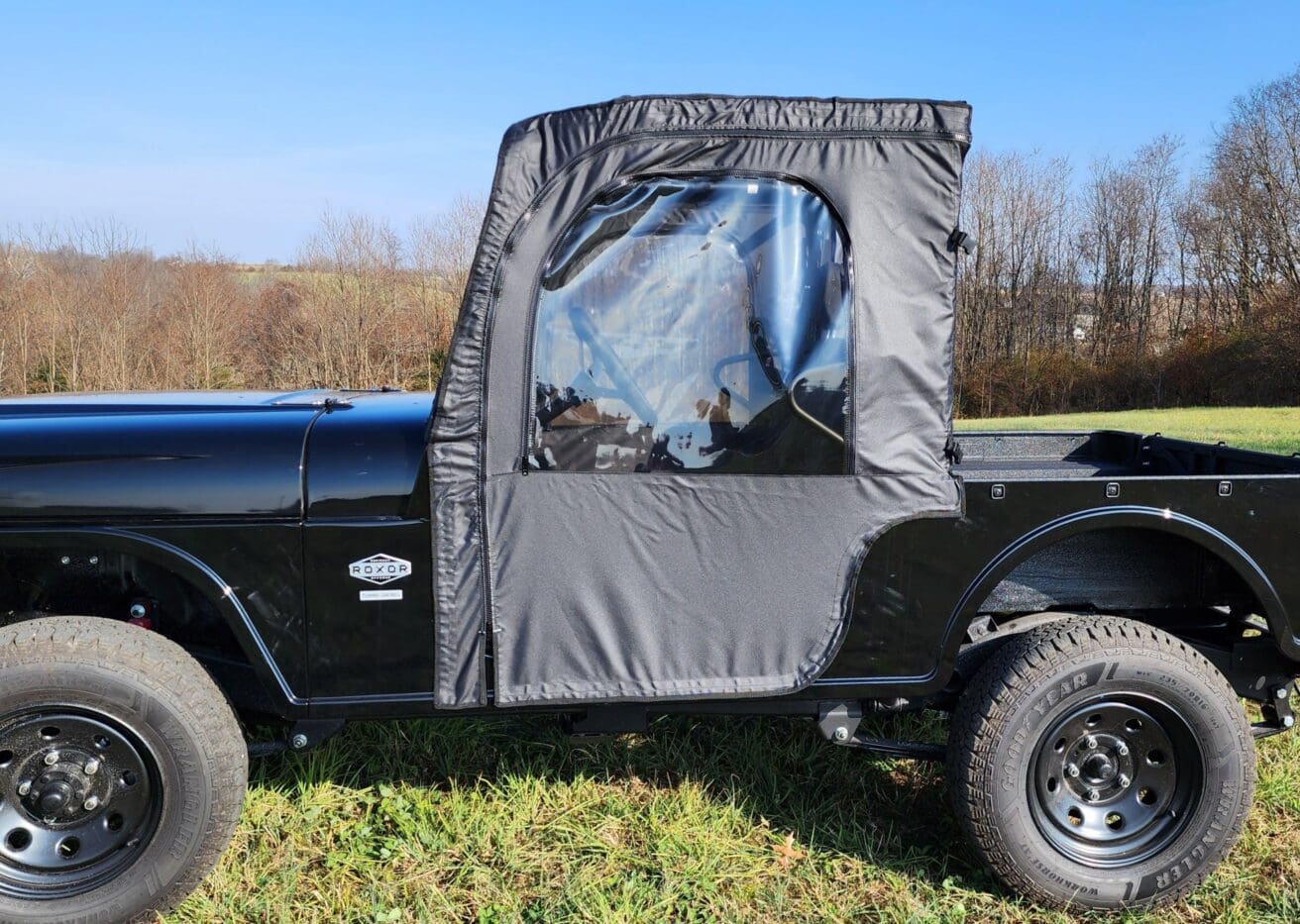A black jeep with a door open in the grass.