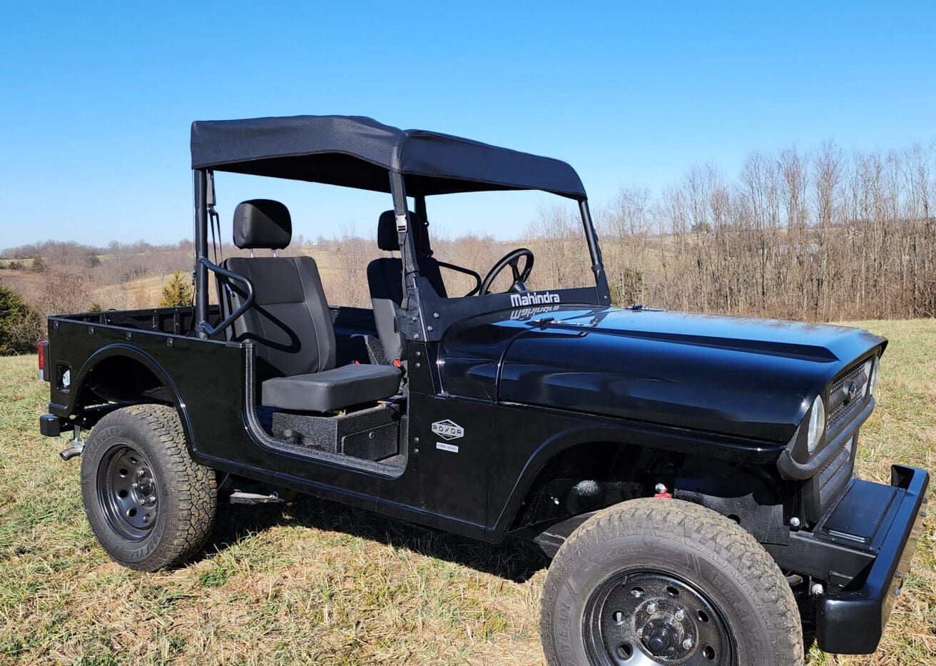 A black jeep is parked in the grass.