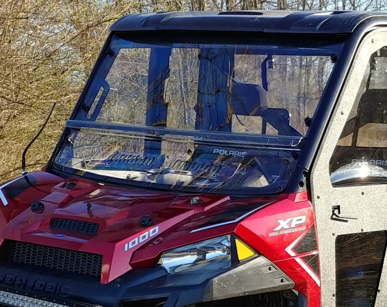 A red truck with its hood up and the windshield broken.