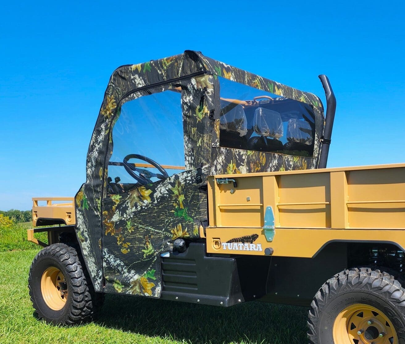 A yellow utility vehicle with camouflage paint on it.