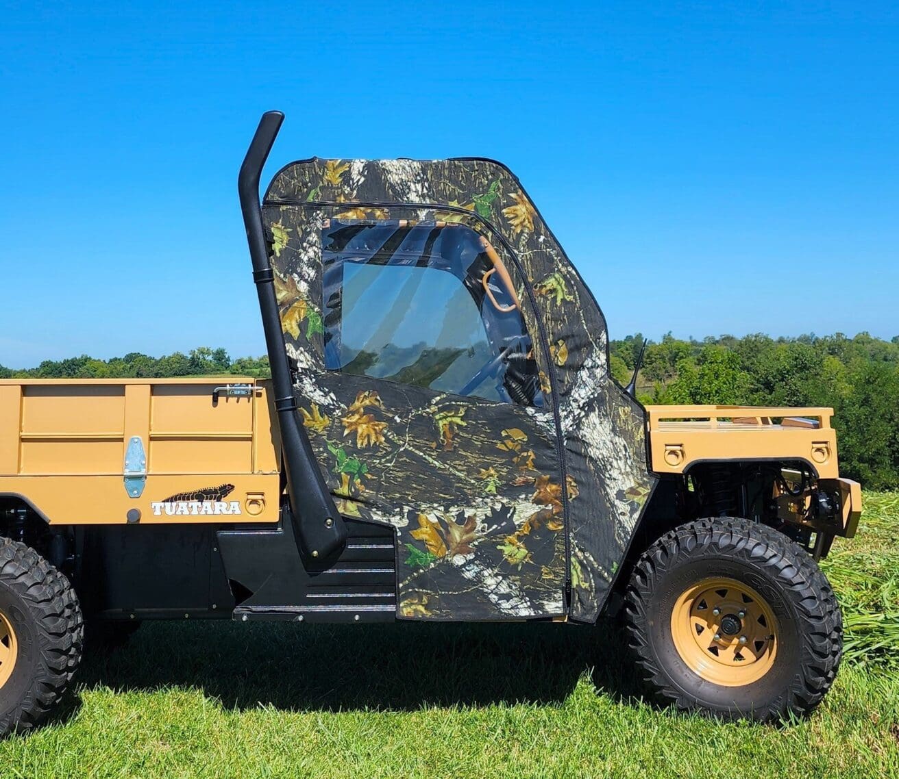 A camo covered utility vehicle parked in the grass.