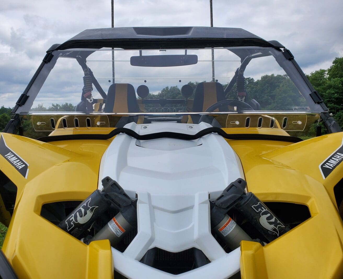 A close up of the front end of a yellow and white vehicle.