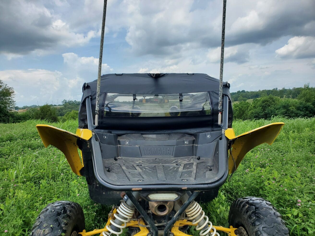 A yellow and black atv parked in the grass.