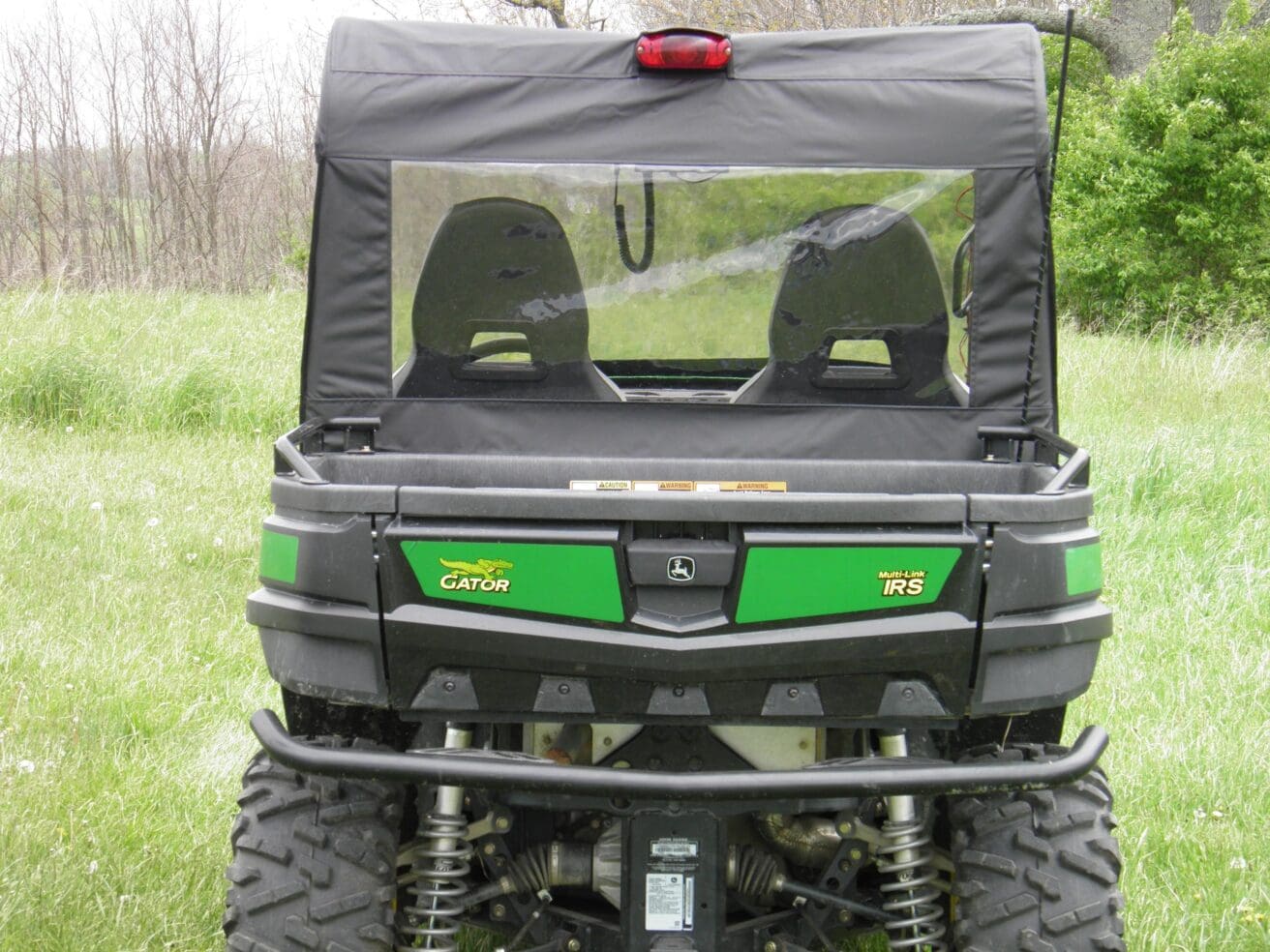 Green utility vehicle parked on grass field.