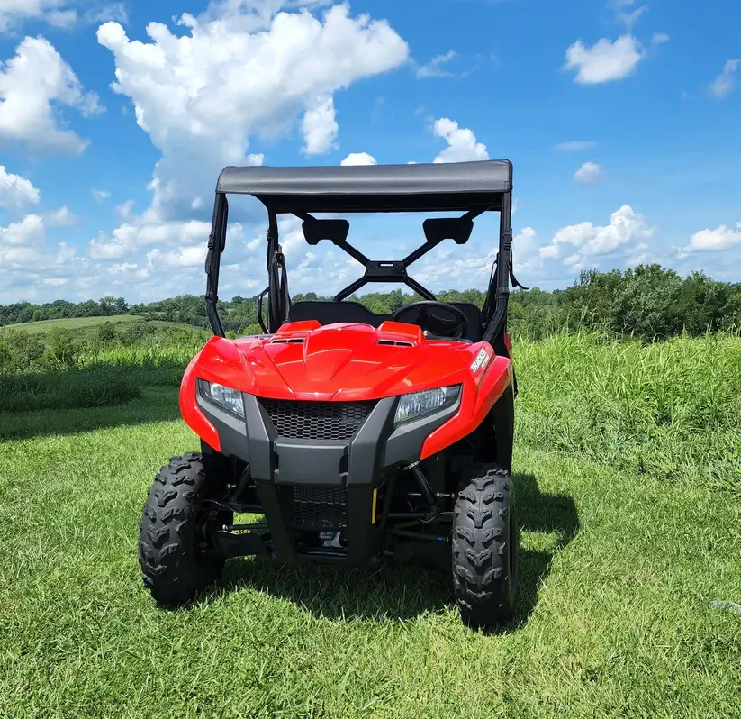 Red ATV on grassy field under sky.