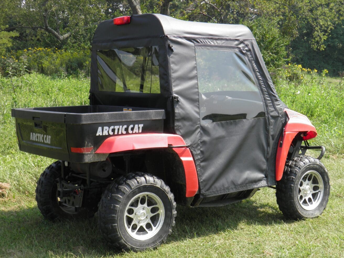 Red Arctic Cat ATV with cabin cover.