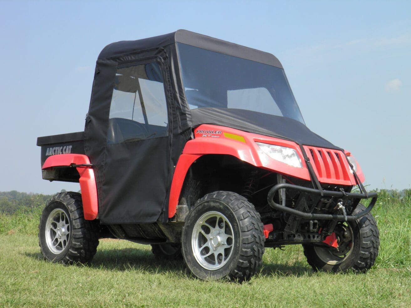 Red utility vehicle parked on grass field.