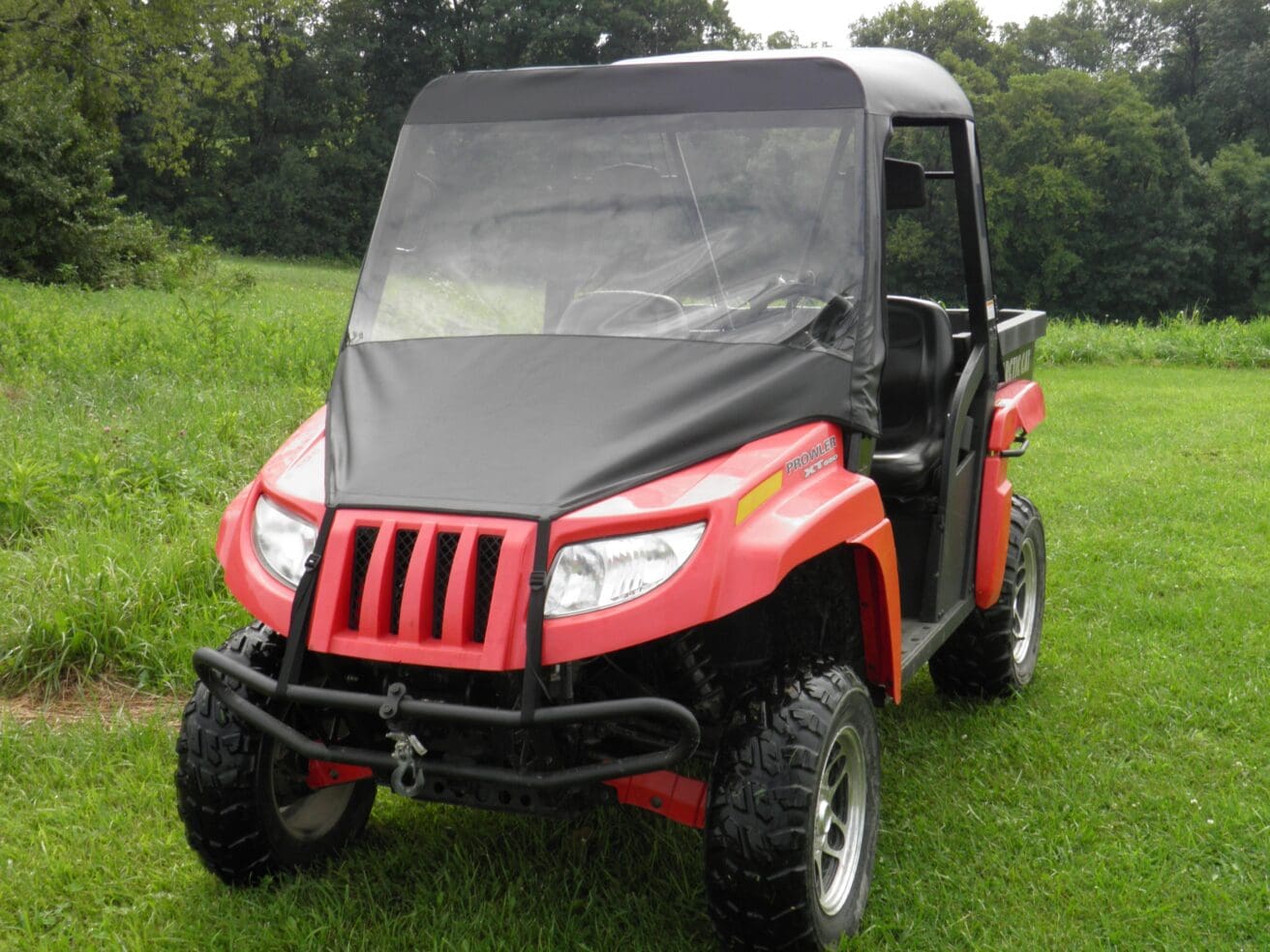 Red off-road vehicle on grass field.