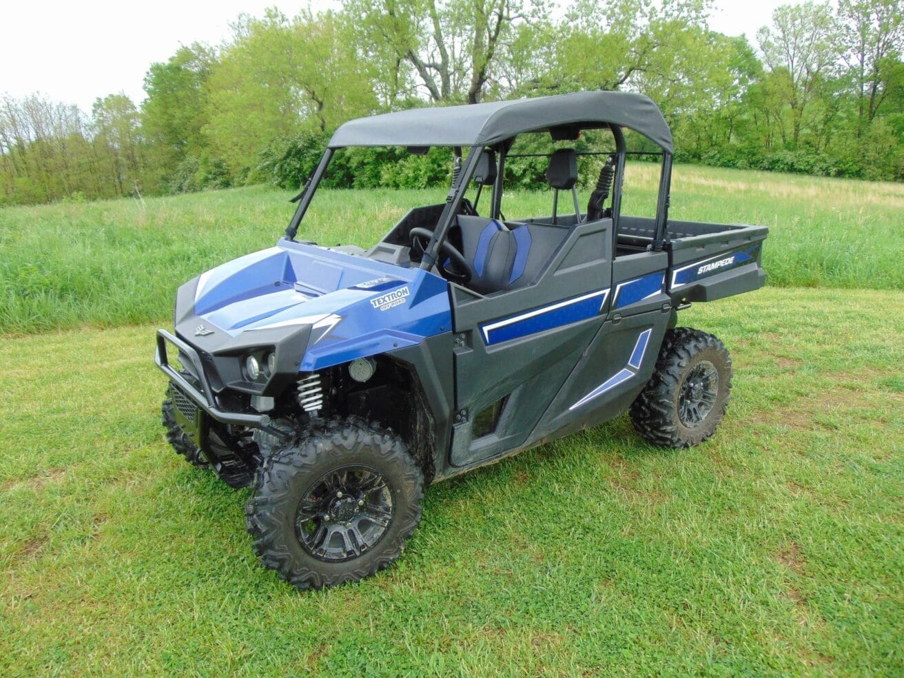 Blue utility vehicle parked on grassy field.