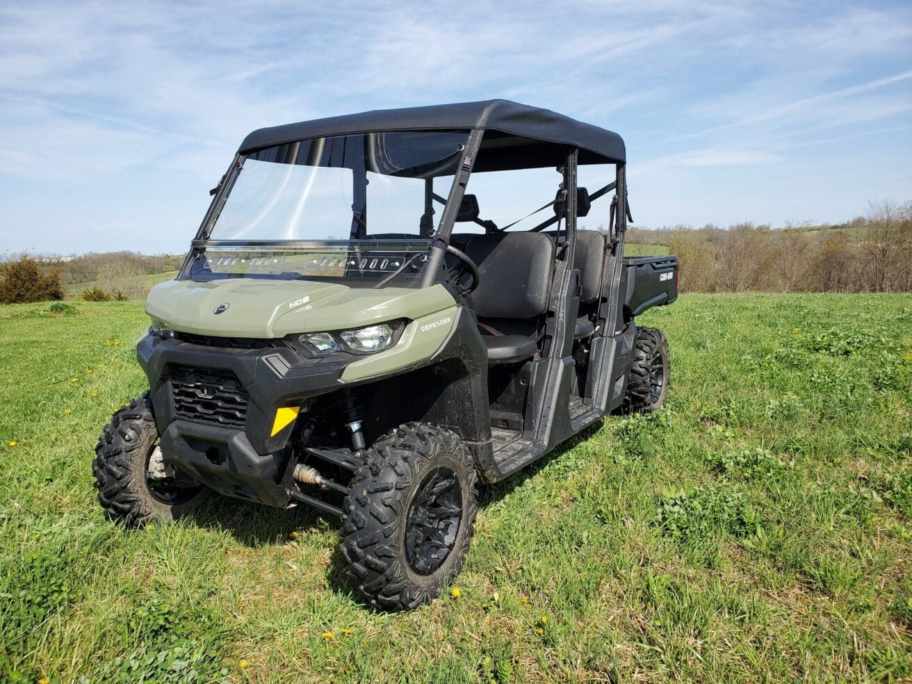 Off-road vehicle on grassy field under sky.