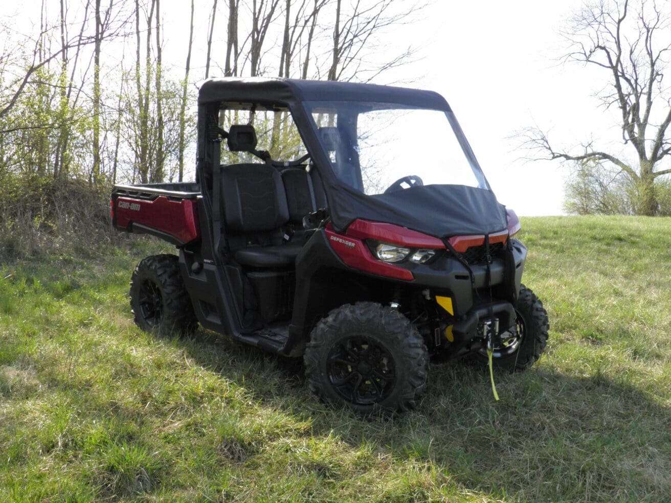 Red ATV on grassy field with trees.