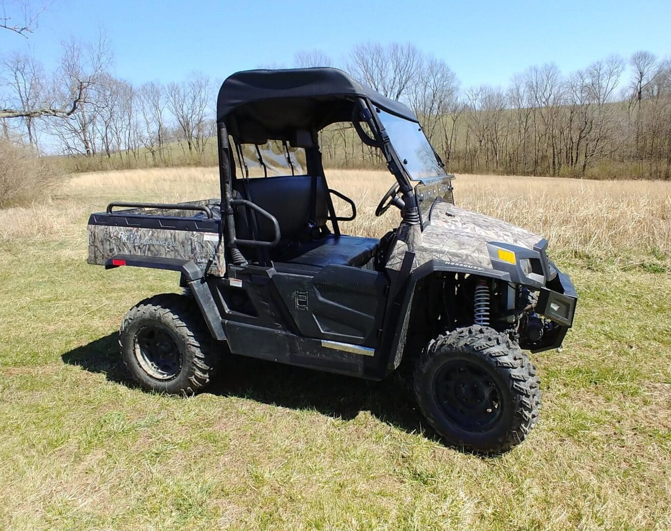 Camouflage ATV parked on grassy field.
