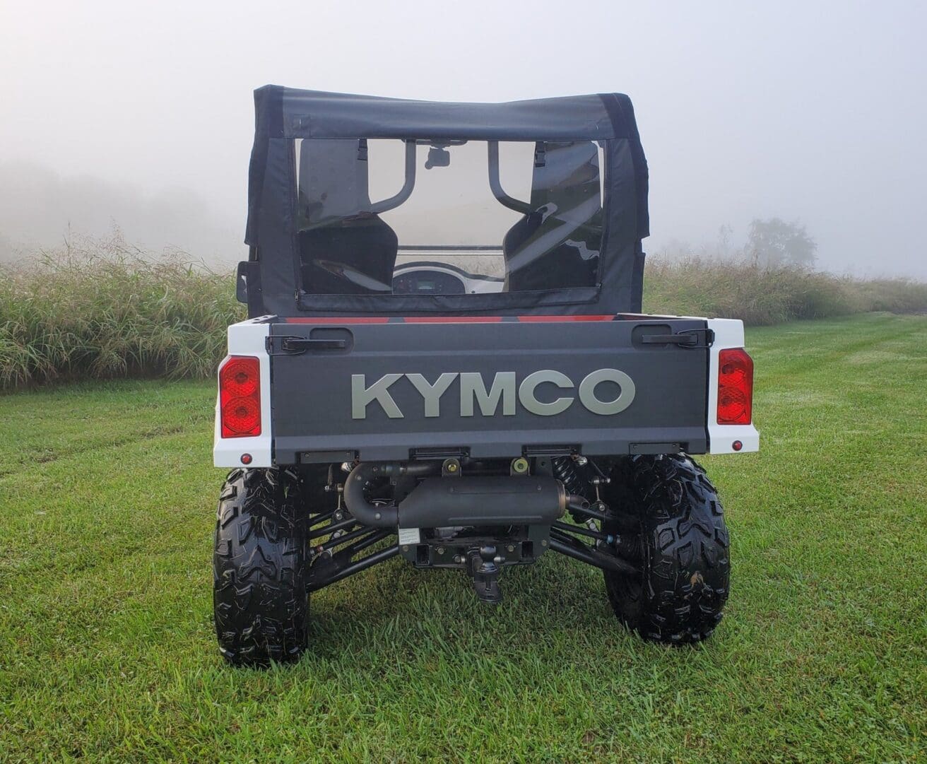 White Kymco utility vehicle in grass.