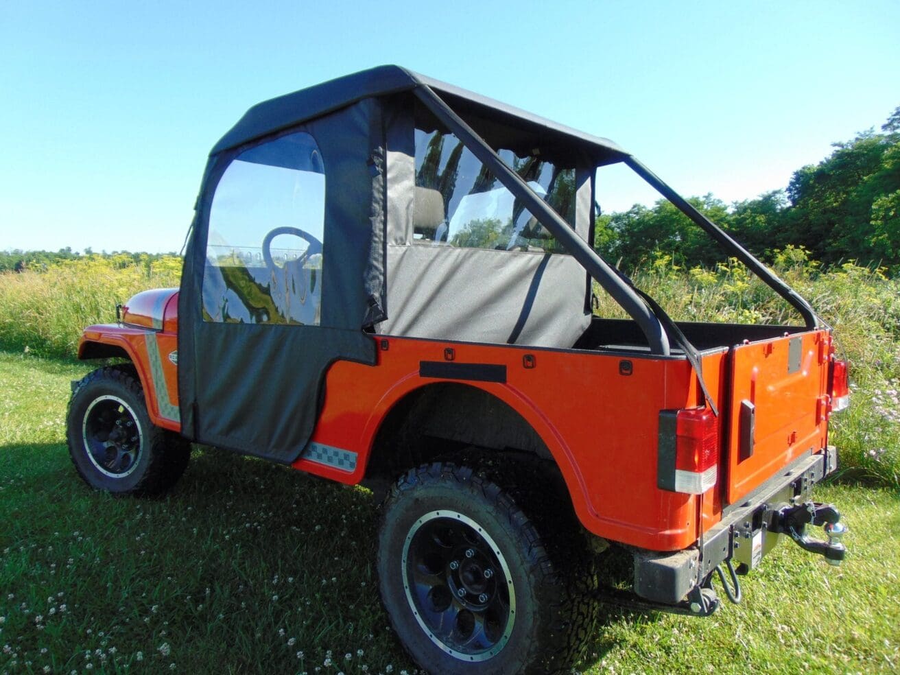 Red jeep with black soft top and roll bar.