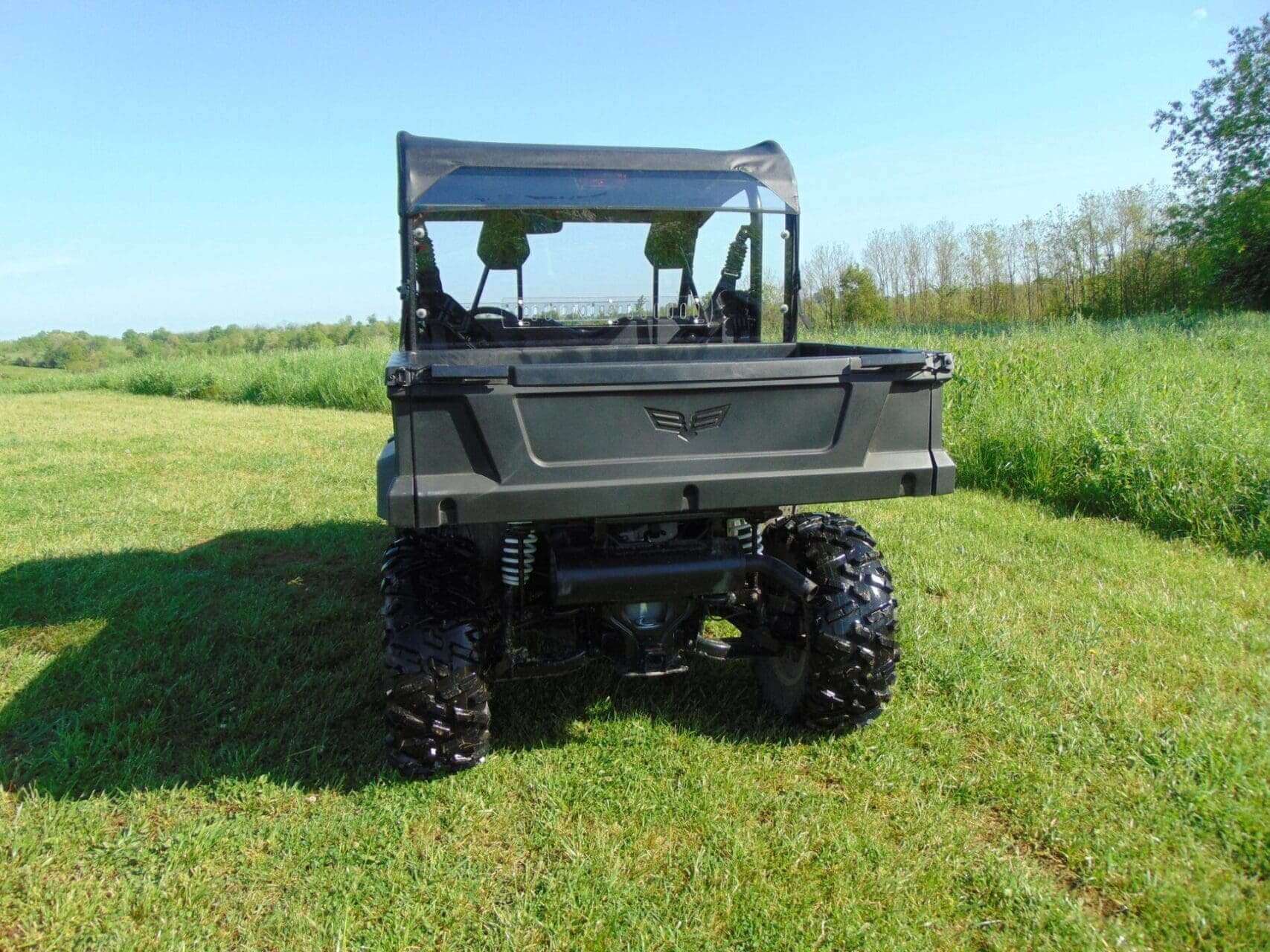 Rear view of black utility vehicle in field.