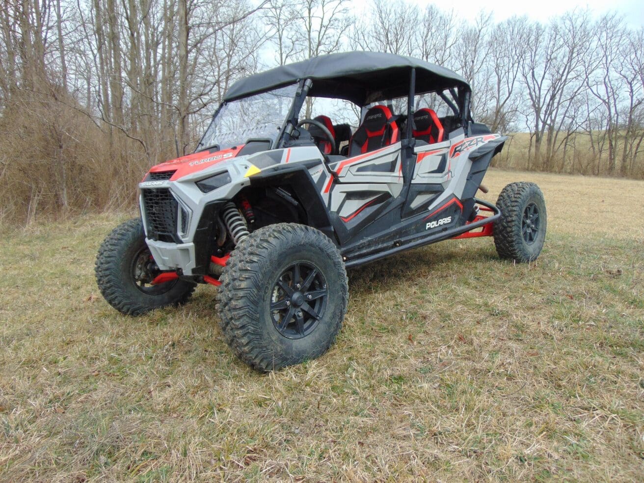 Grey and red Polaris RZR in field.