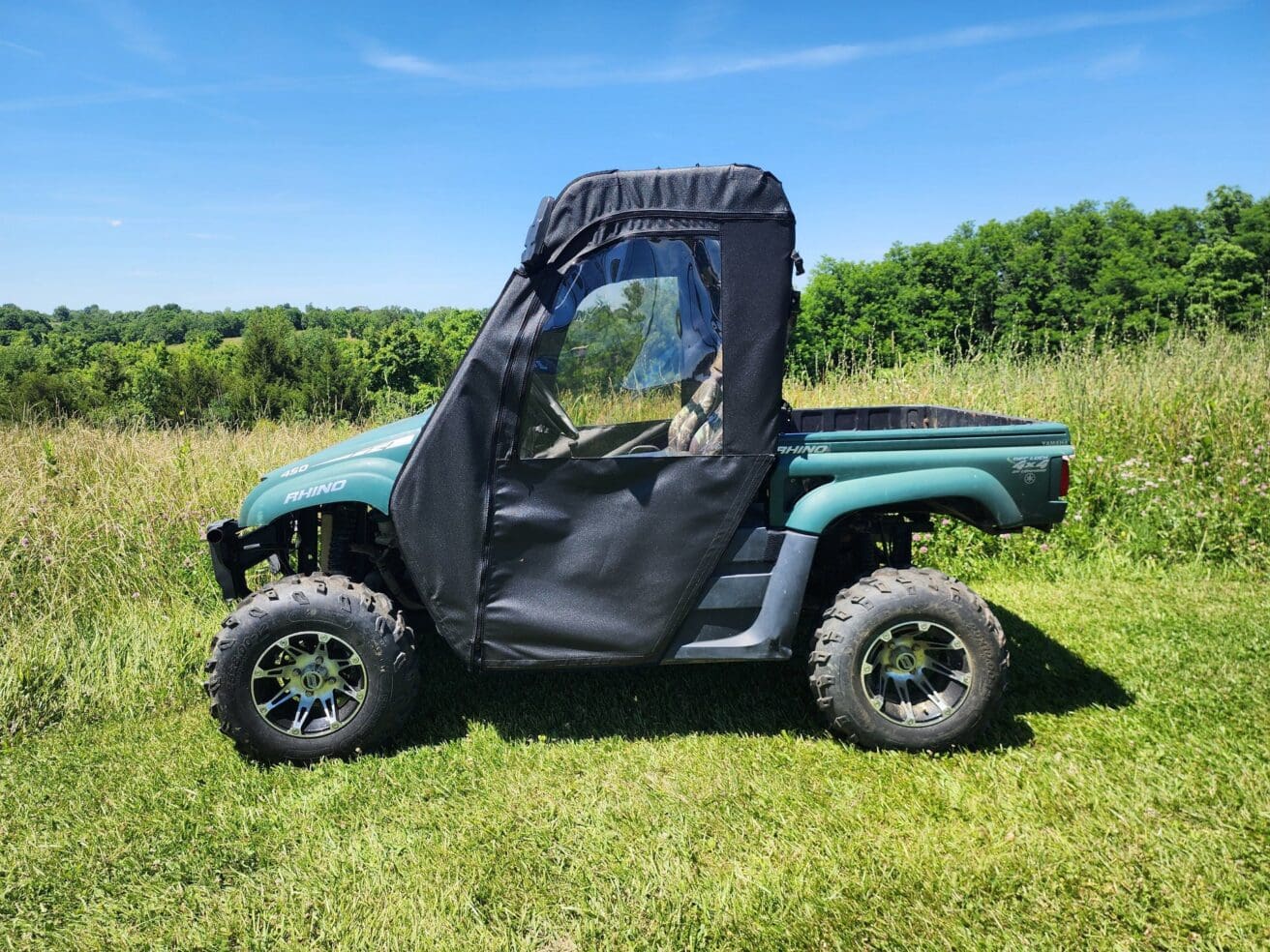 Green Yamaha Rhino in grassy field.