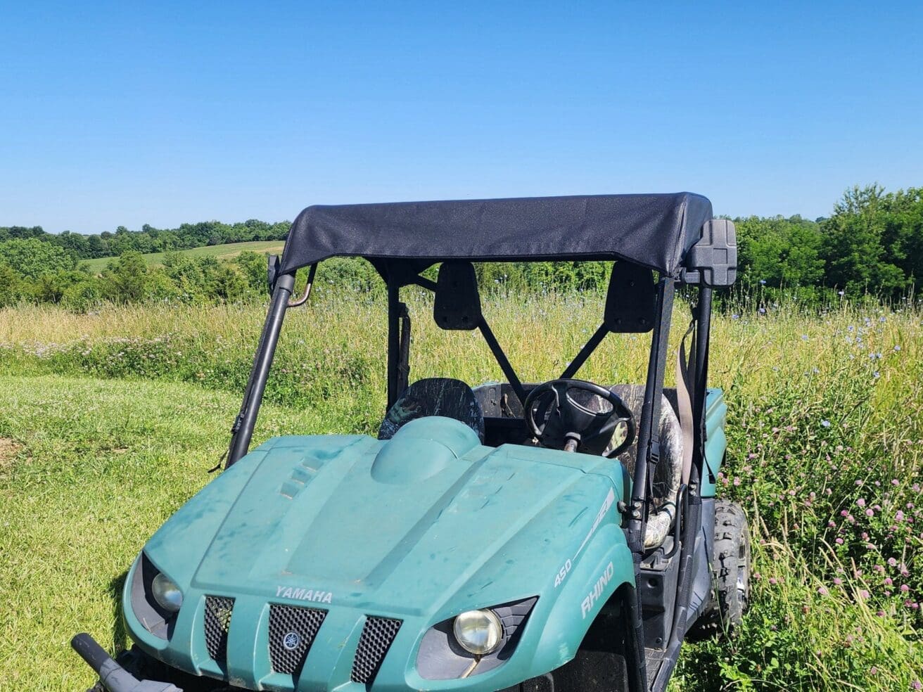 Teal Yamaha Rhino ATV in field.
