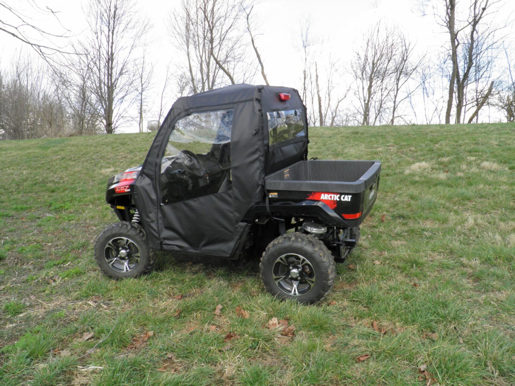 Black Arctic Cat UTV parked on grassy field