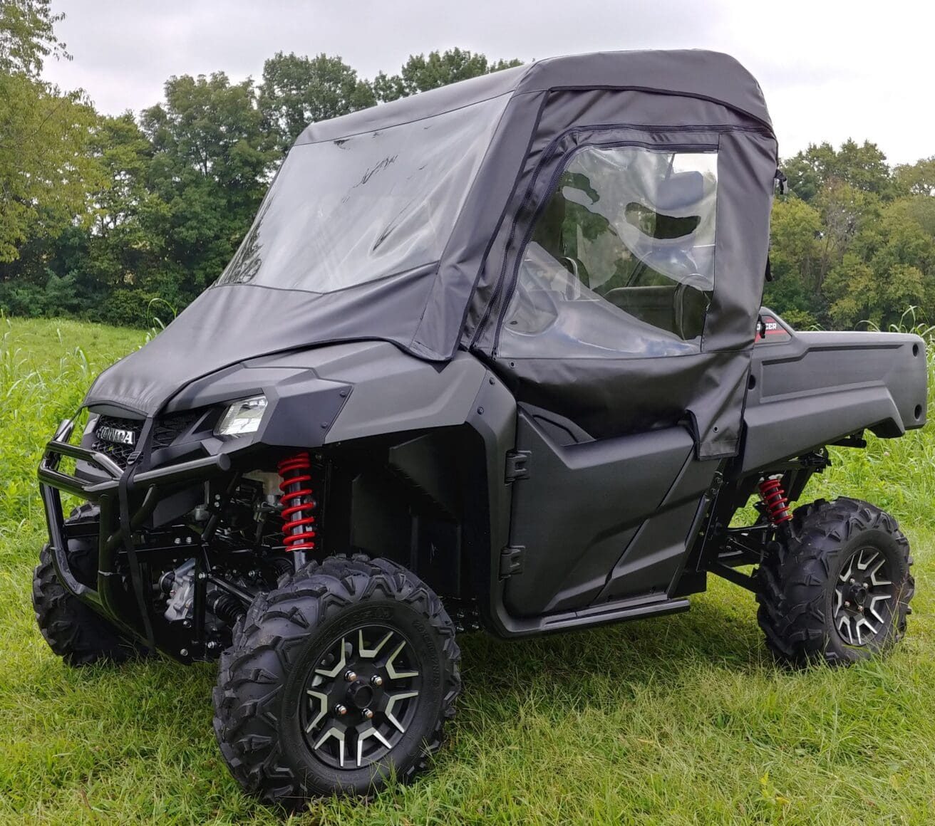 Black enclosed UTV parked in grassy field