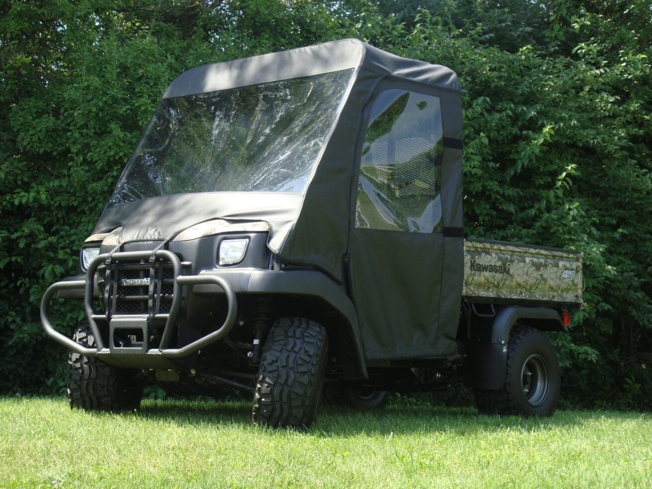 Covered Kawasaki utility vehicle parked on grass