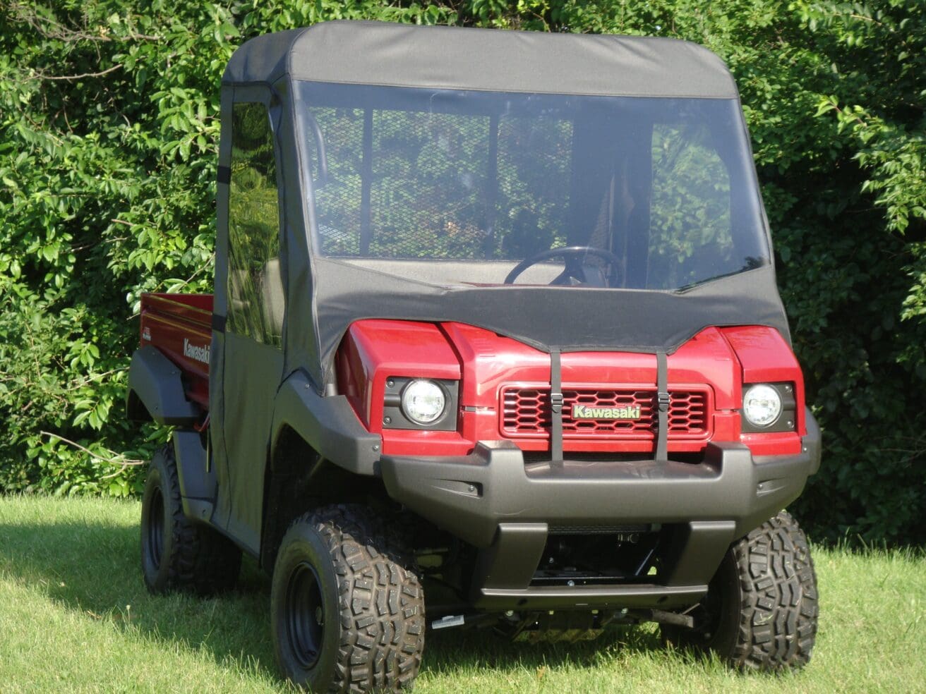 Red Kawasaki UTV parked on grassy lawn