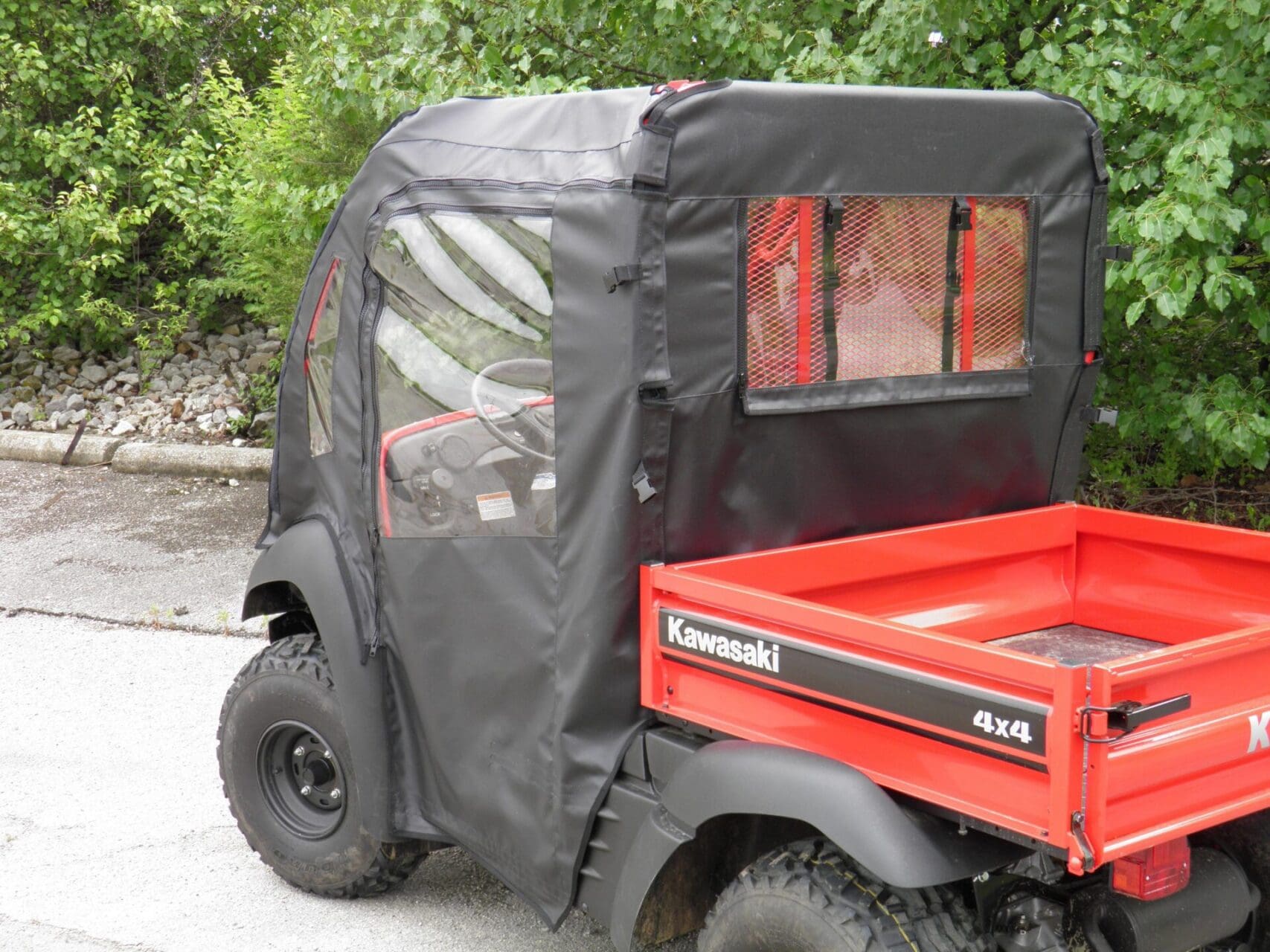 Red Kawasaki 4x4 utility vehicle with enclosure