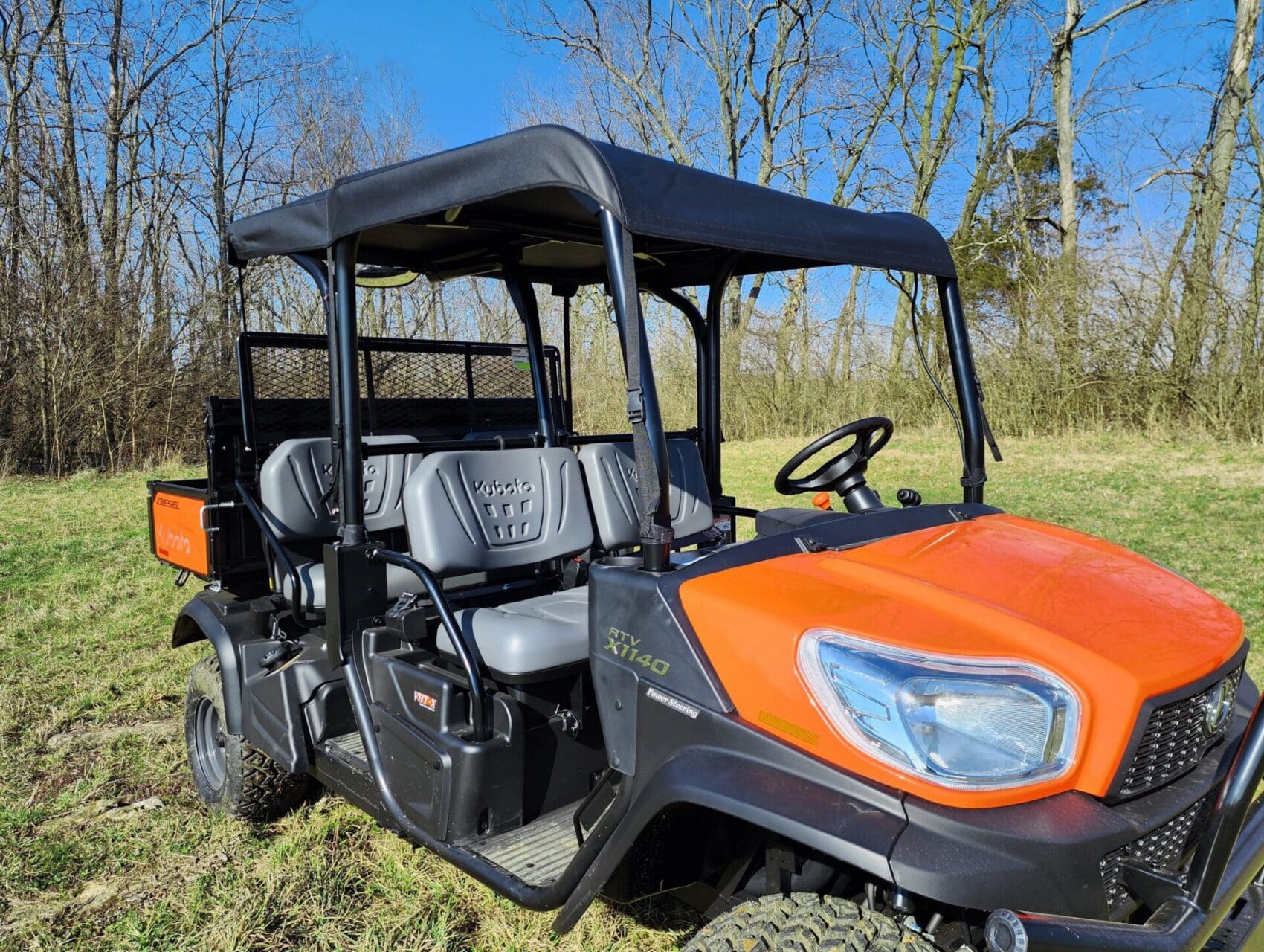 Orange utility UTV parked on grassy field