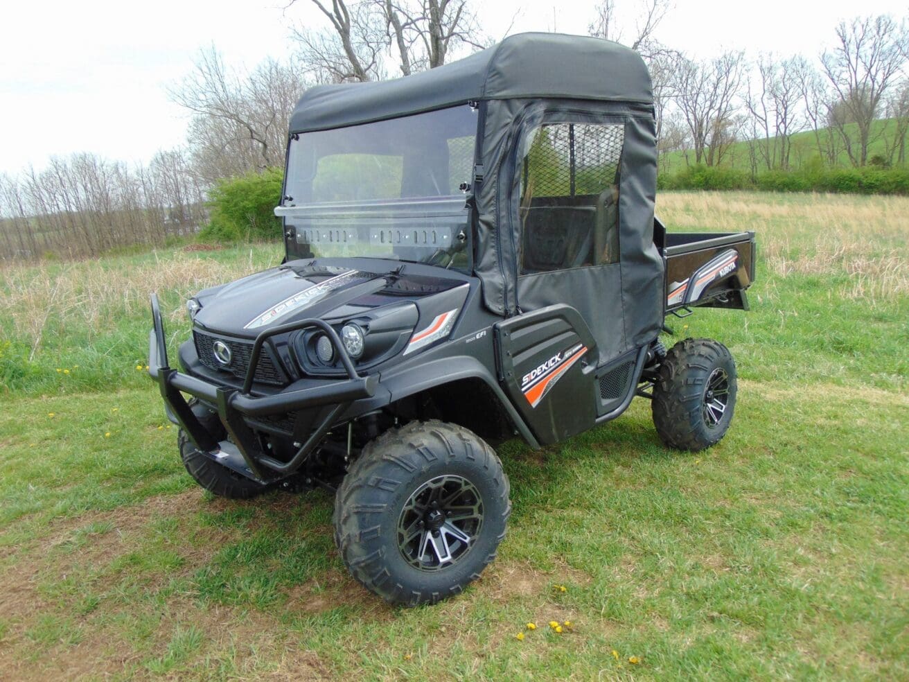 Black enclosed side-by-side UTV parked on grass