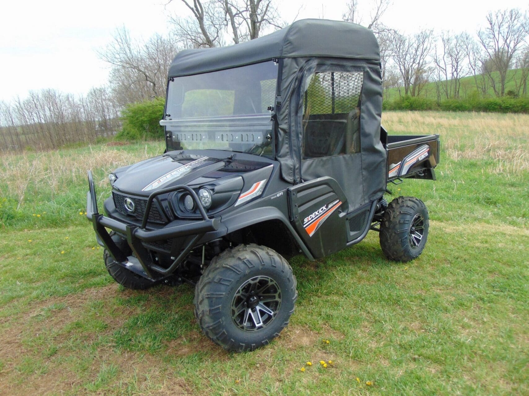 Black enclosed side-by-side UTV parked on grass
