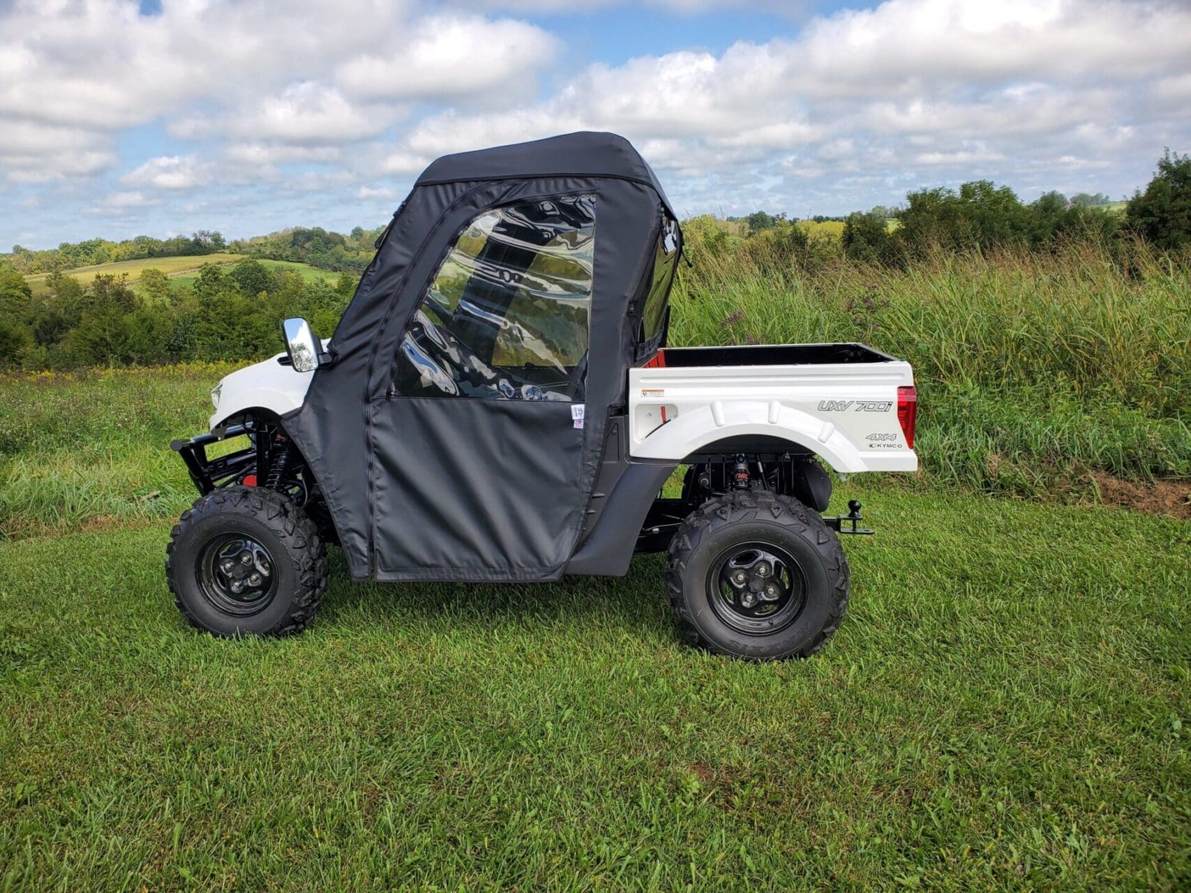 Utility vehicle with soft enclosure in grass.