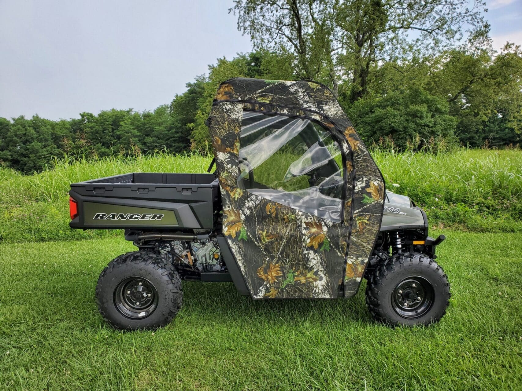 Camouflage enclosure on utility vehicle outdoors.