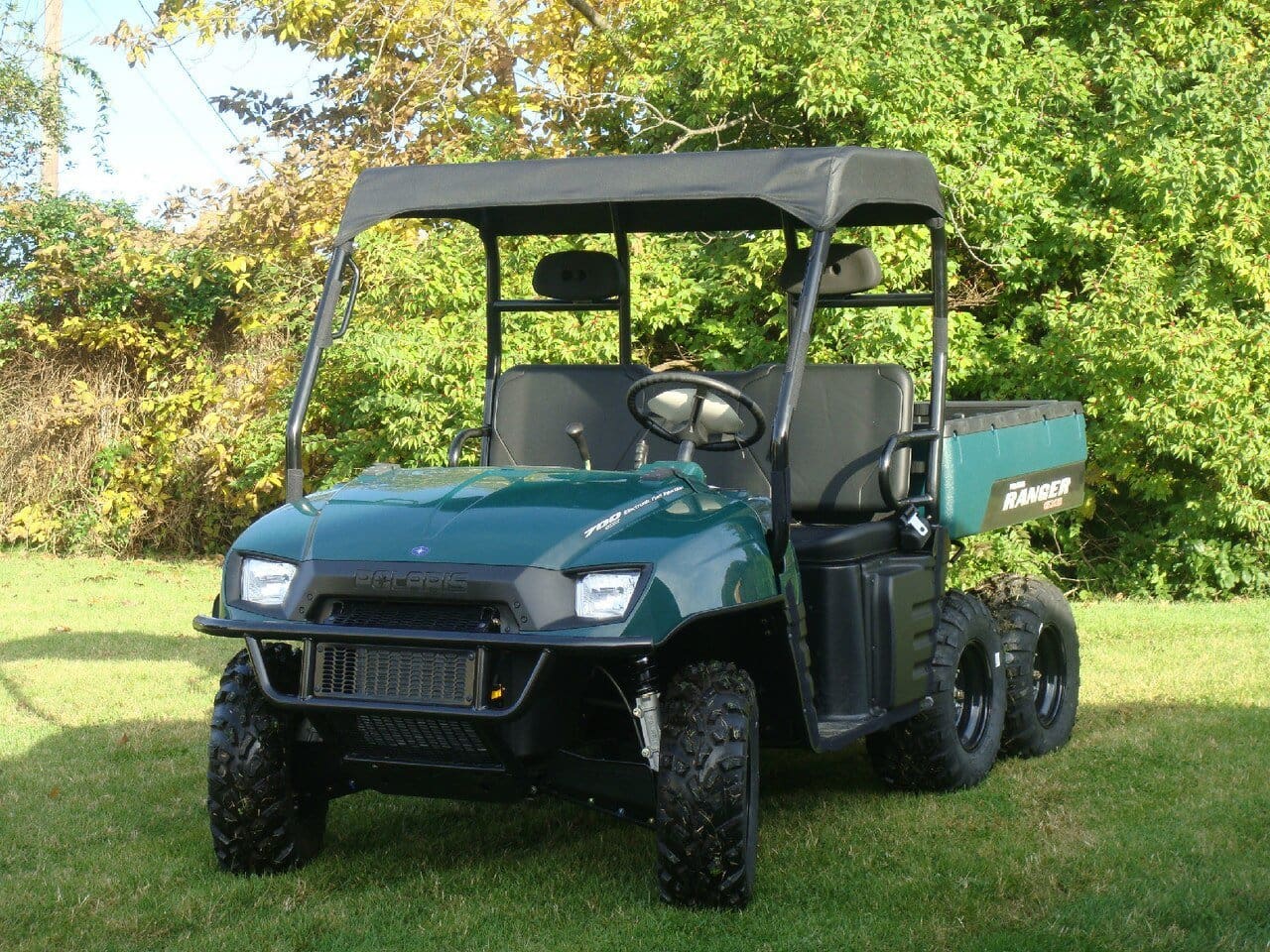 Green utility vehicle parked on grassy terrain.