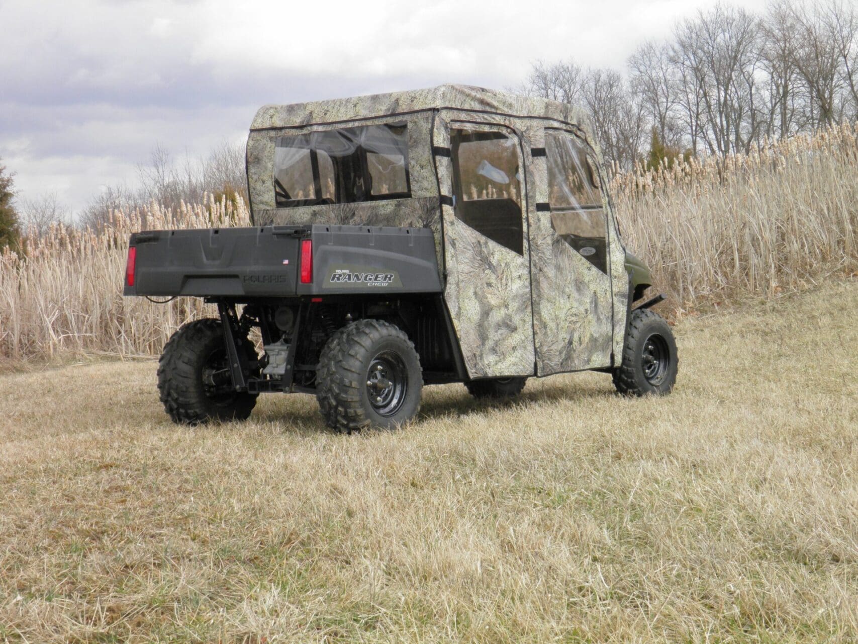 Camouflaged utility side-by-side vehicle in field
