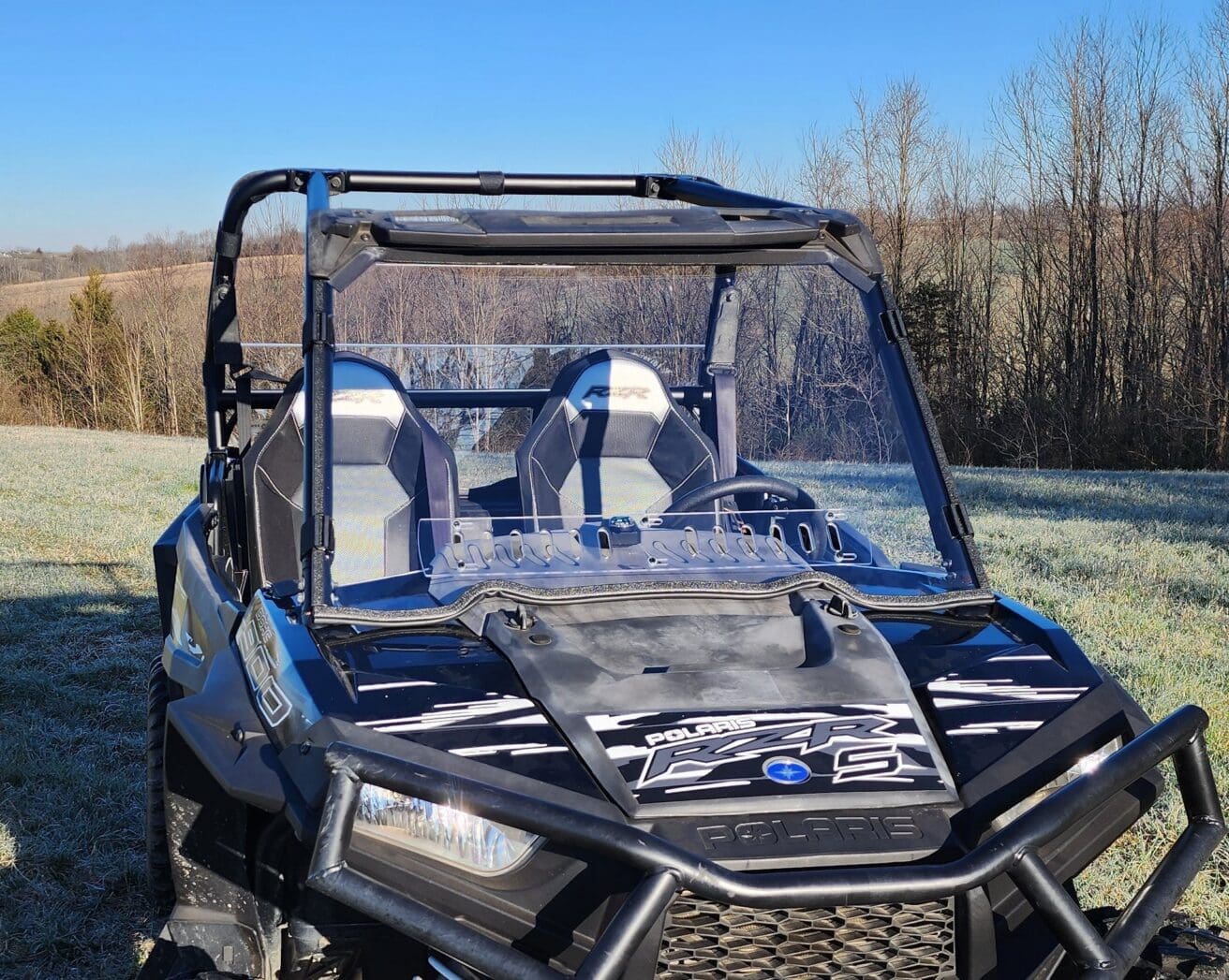 Black Polaris RZR two-seat UTV parked in field