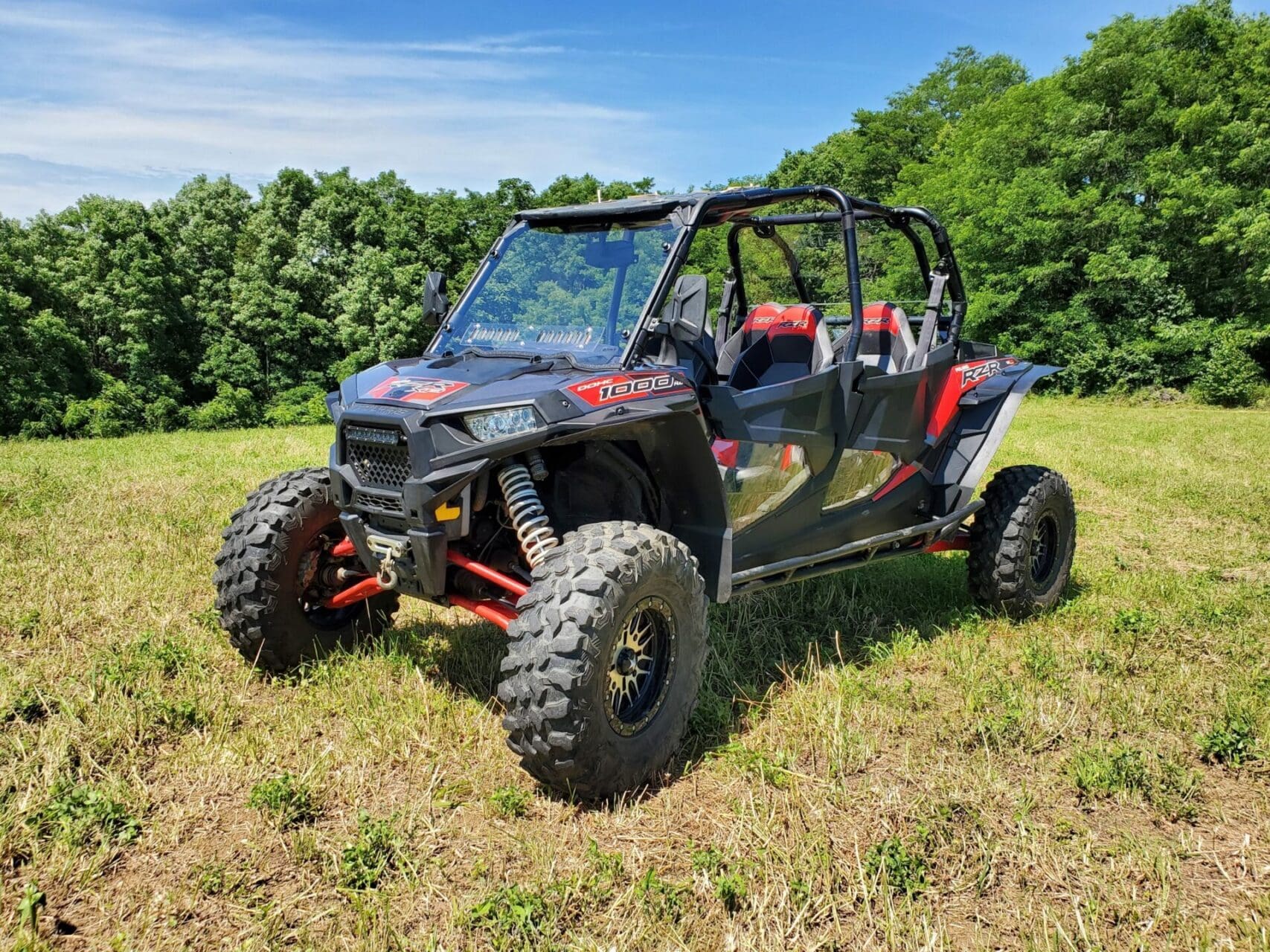 Black and red off-road UTV in grassy field